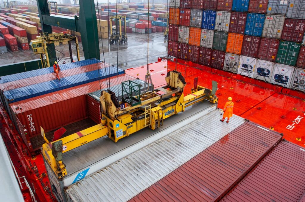 Aerial view of workers managing cargo loading at a bustling port with vibrant shipping containers.